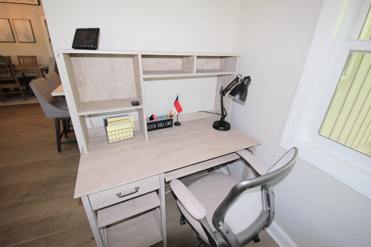 A dedicated workspace with a desk, monitor, lamp, and shelving, set up for focused productivity. Flags and decor add personality while the scene conveys a sense of inspiration and efficient remote work.