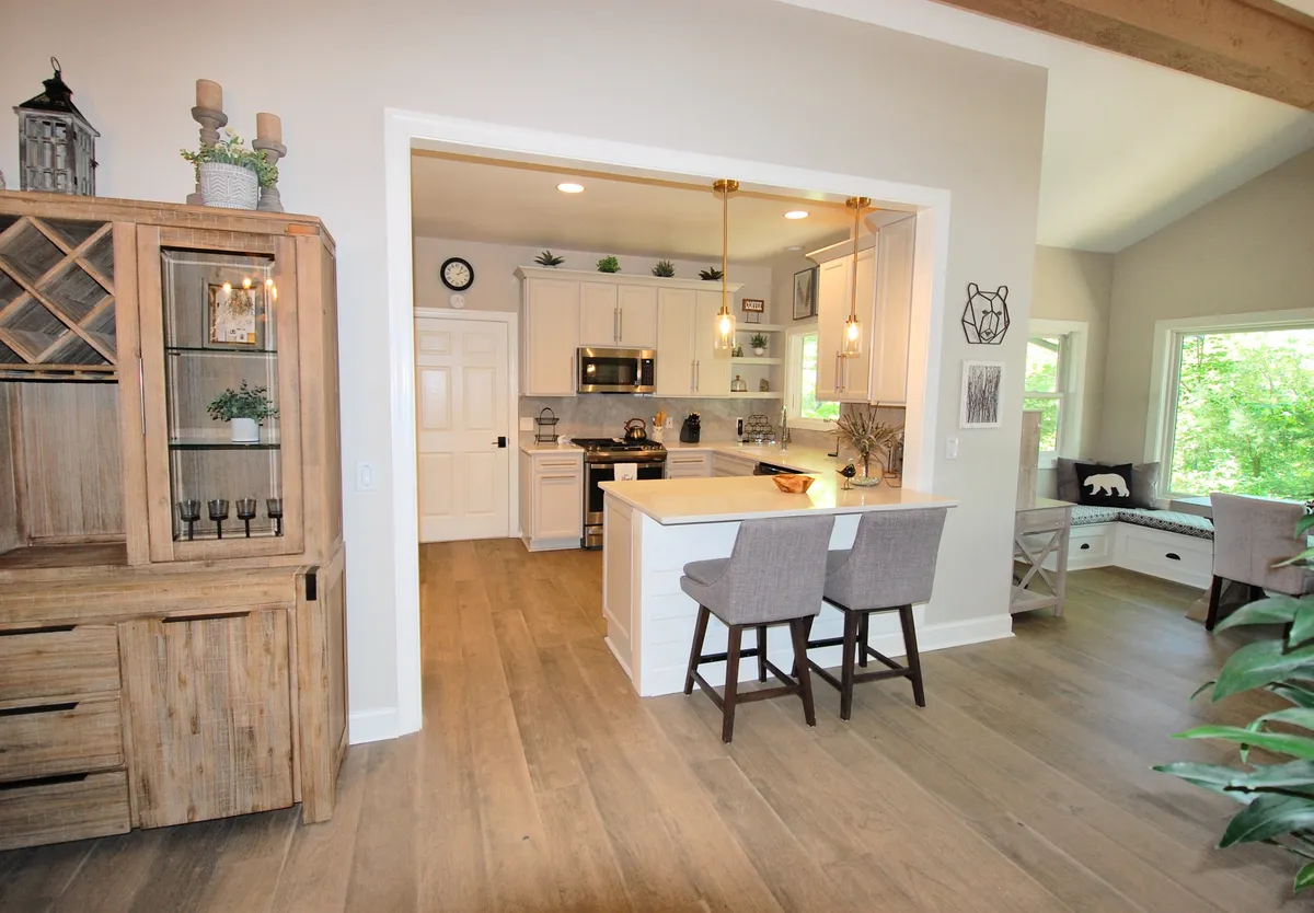 A warm, inviting interior featuring a spacious kitchen island, elegant wooden cabinetry, and an adjacent dining area. Large windows bring in ample daylight, and the layout is ideal for cooking, entertaining, and gathering for meals.