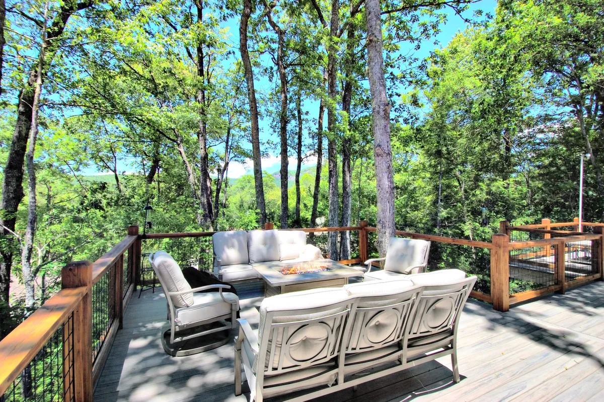 A serene outdoor seating area on the deck, complete with a coffee table and surrounded by greenery. The arrangement invites both quiet moments and social gatherings, set against a tranquil, inviting backdrop.