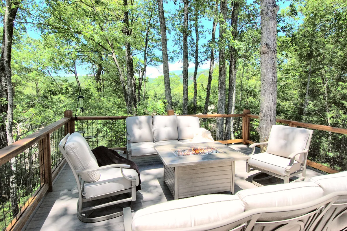 The hero image showcases the exterior of Jessamine Cottage nestled among towering trees, with an inviting outdoor seating area encircling a cozy fire pit. The setting exudes tranquility, offering a perfect space for guests to relax, gather, and immerse themselves in the surrounding natural beauty.