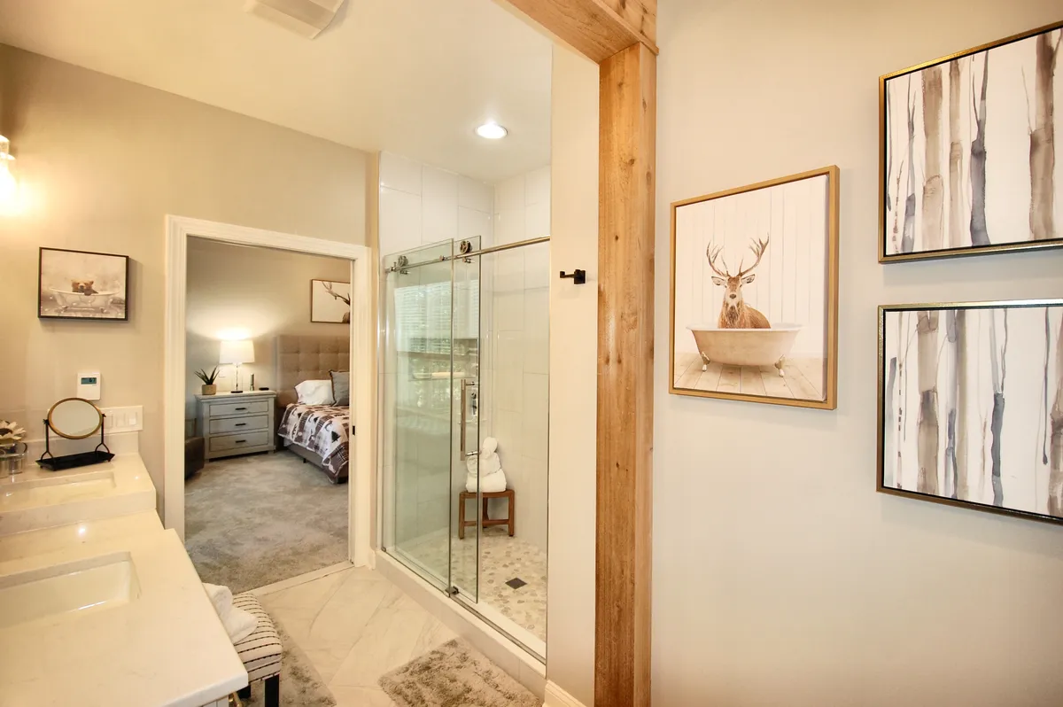 A tranquil bathroom scene focusing on a vanity area, a sleek shower enclosure, and framed art on the wall. The atmosphere is calm and inviting, ideal for self-care routines or unwinding at the end of the day.